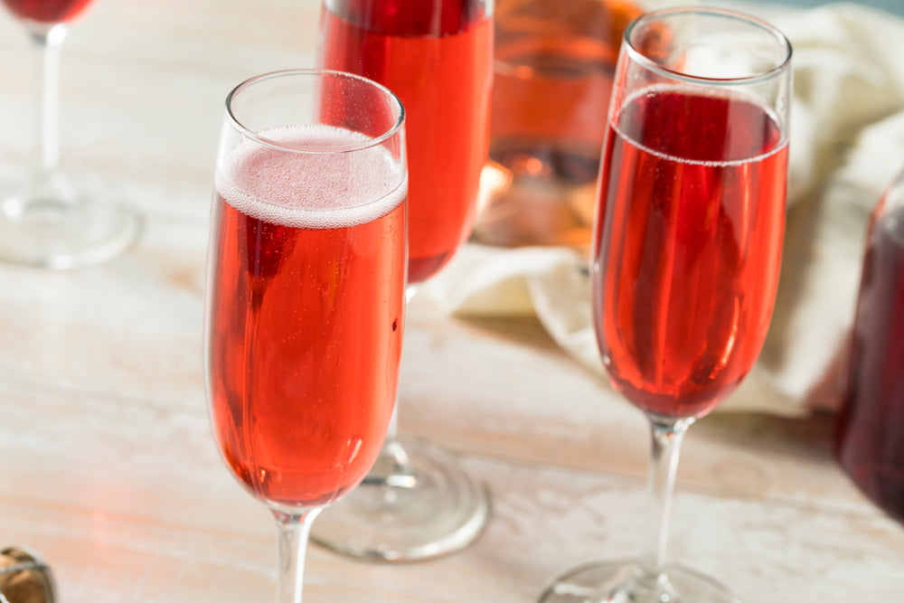 three glasses of pink mimosa cocktail on top of a marble table with a white folded table cloth on the side