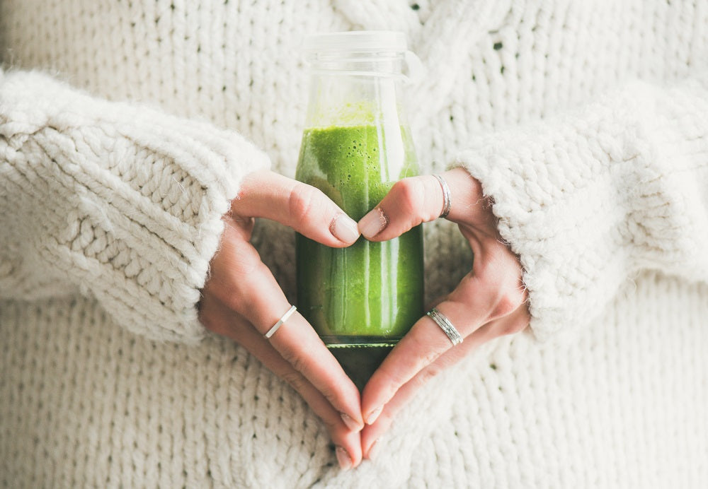 image of woman with a green juice and white sweater