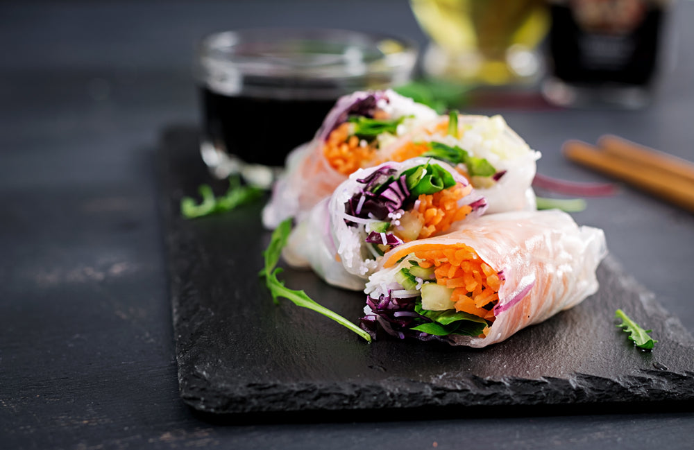 Three pieces of rainbow rolls next to a saucer of almond sauce